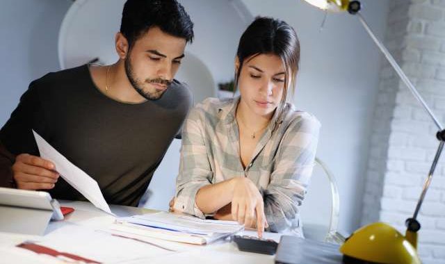 Young couple reviewing invoices and doing family business plan. Concept of money and economic problem for man and woman living together